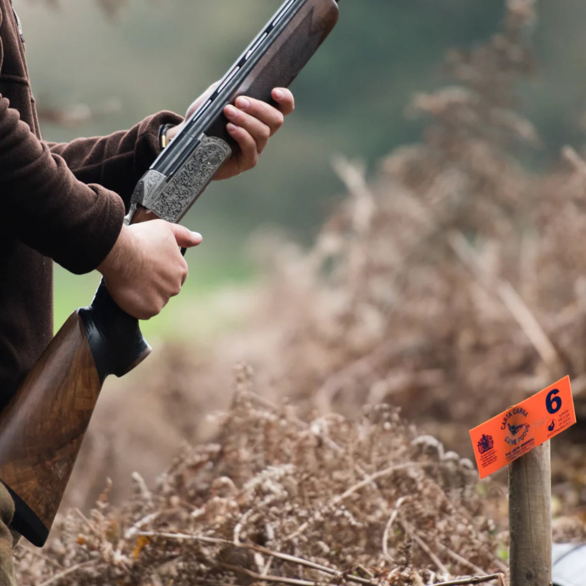 Hunter holding a shotgun beside a MNR tag